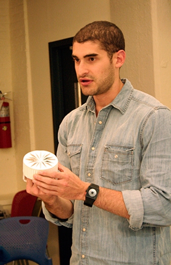 A man wearing a jean shirt and holding a white cylindrical object.