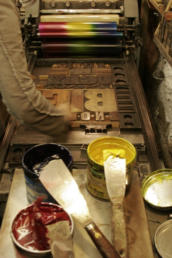 A photo of a typographic machine being set up with paint and metal letters.