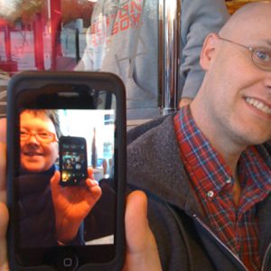 A photo of a man holding a phone showing a photo of a man holding another phone.