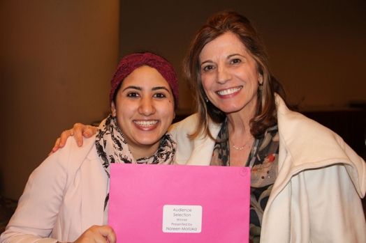 A photo of two women holding a pink envelope with a label on it.