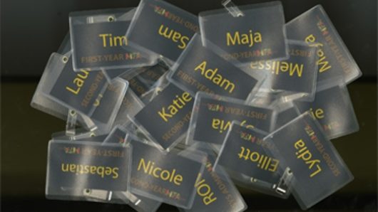 An image of a pile of transparent gray tags with yellow text names on them.