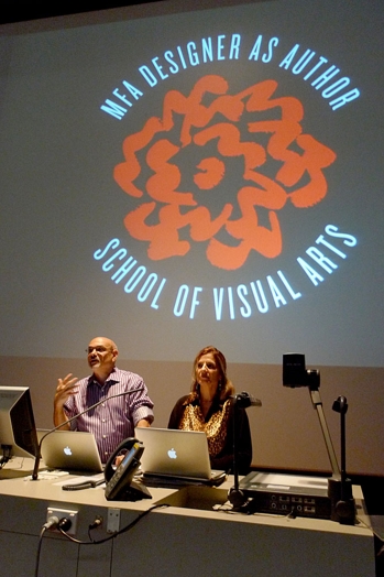 A photo of two people giving a lecture while behind them there is a projector screen with a logo and text: MFA DESIGNER AS AUTHOR, SCHOOL OF VISUAL ARTS.