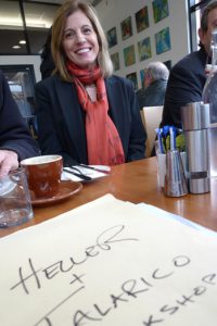 A photo of a woman wearing a red scarf while having coffee at a restaurant.