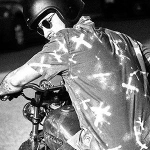 A black and white image of a man on a bike.