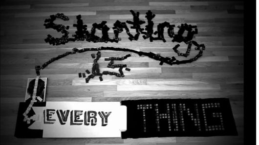 A black and white photo of a domino game that forms the text: Starting is Every Thing.