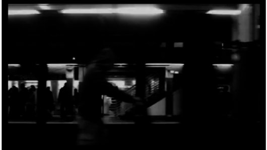 A black and white photo of people in a subway station.