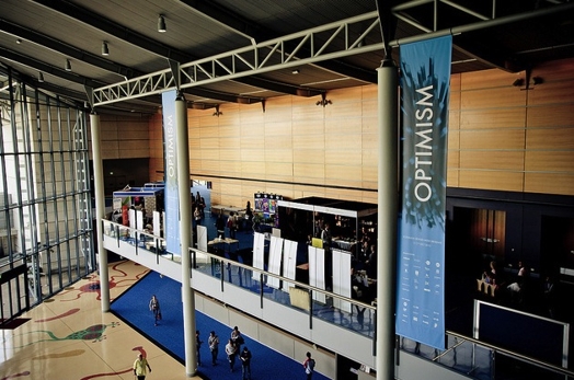 A photo of a hallway that has some blue banners attached to the pillars with the text: Optimism.