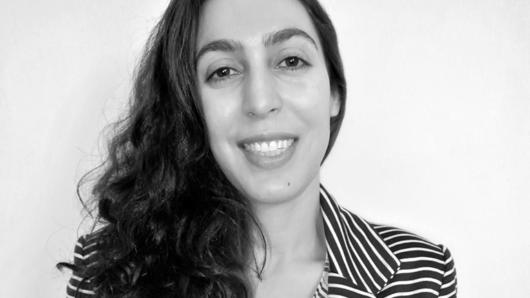 A black and white photo of a woman smiling while wearing a striped shirt.