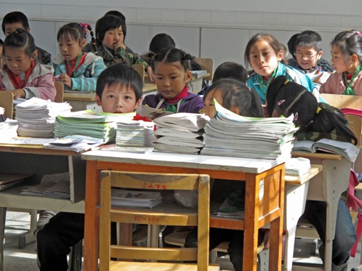 A photo of some Asian looking children sitting in a classroom.
