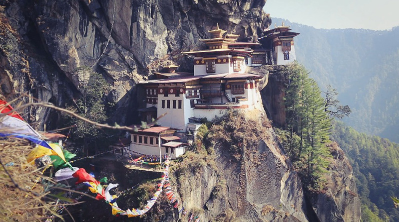 A photo of what looks like a mountain monastery and some line with colored scarfs on it. The locations seems to be somewhere in Asia.