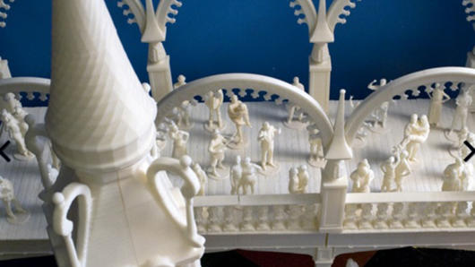 A photo of some white 3d print showing a castle tower and a bridge filled with figurines looking like people.