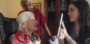 A photo of a woman showing something on a tablet to an older woman, while a third person is watching.
