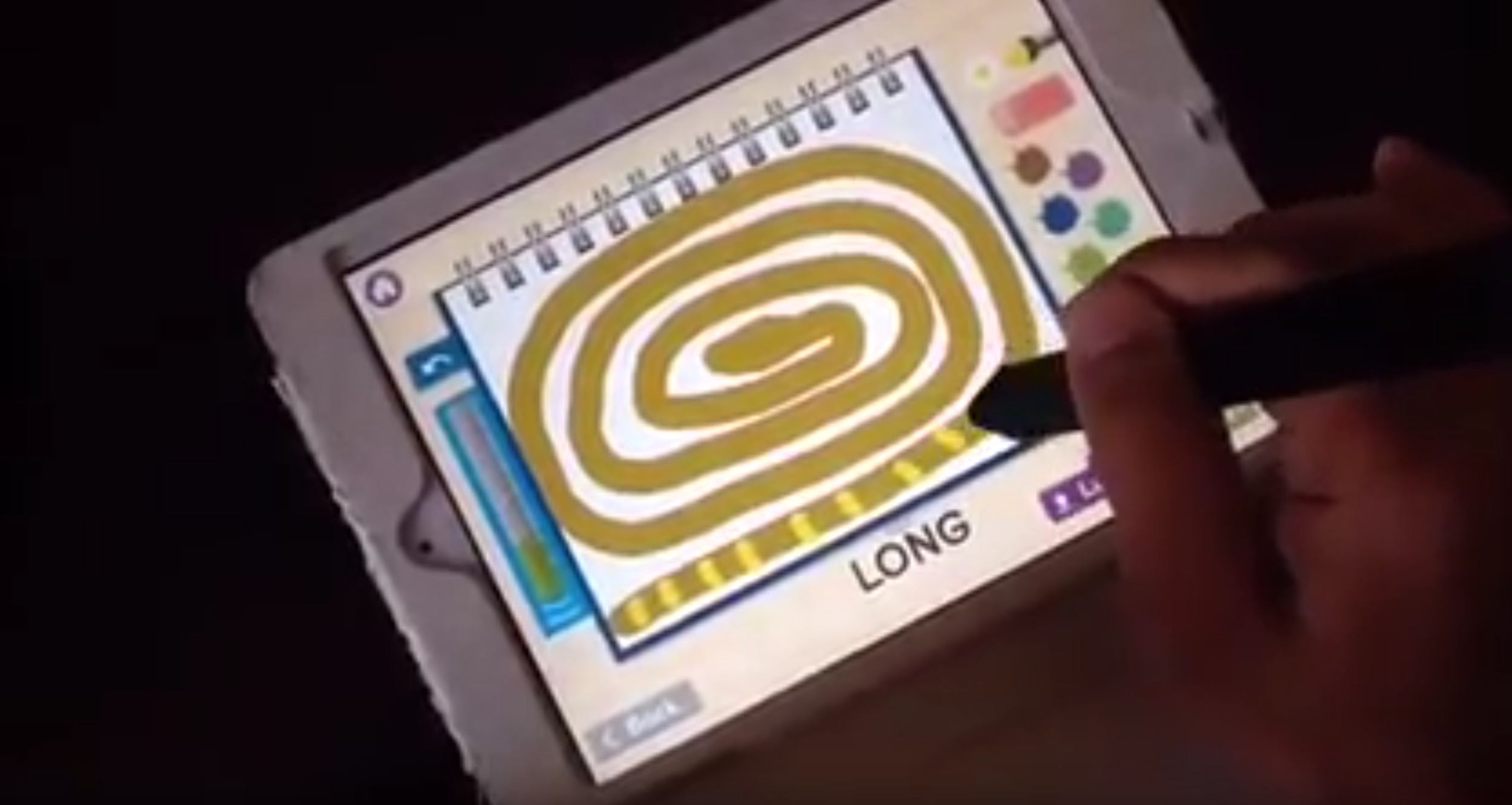 A photo of a hand holding a pen and drawing a snake figure on a tablet.