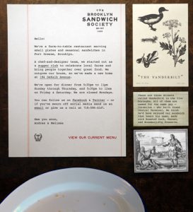 A photo of some pieces of papers with text and drawings on them. One has the title: Brooklyn Sandwich Society.