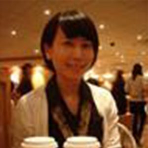 A photo of a smiling woman wearing a white coat.