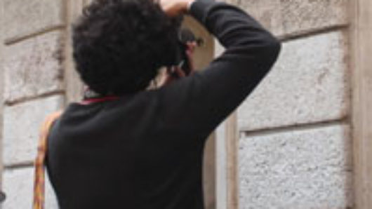 A photo of a man taking a picture of some text engraving on a building.