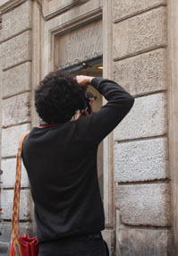 A photo of a man taking a picture of some text engraving on a building.