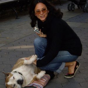 A photo of a woman petting a dog on the street.