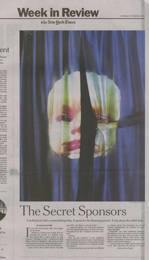 A photo of a newspaper showing an image of a blue curtain and a babyface on it. The title of the news article is: The Secret Sponsor.