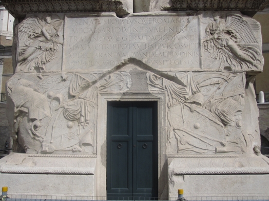 A photo of a door and a stone wall engraved with different figures and letters.