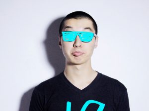 A photo of a man wearing glasses that have a cyan color paint over them.