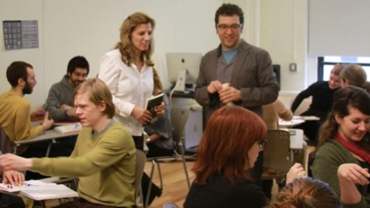 A group of people sitting in a classroom in smaller groups and discussing.