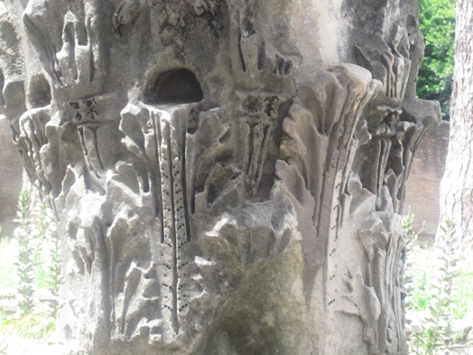 A photo of a stone pillar engraved with with different floral patterns.
