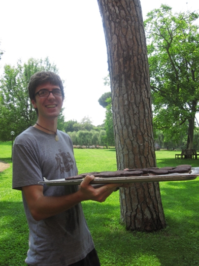 A photo of a man with a stake dish near a tree.