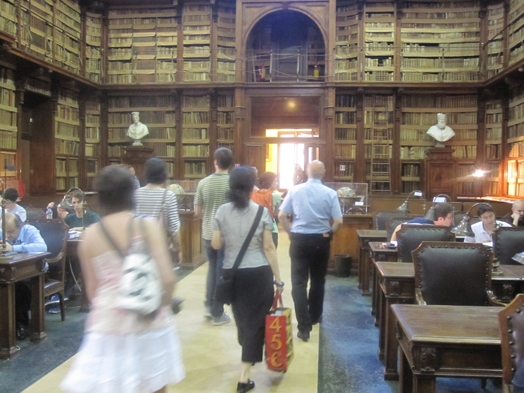 A group of people walking in an old multistore library.