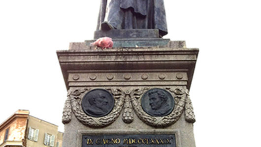 A photo of a statue depicting a person and a plaque on it's base with some text.