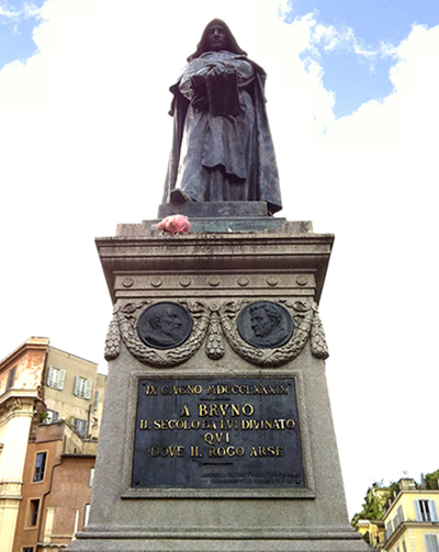 A photo of a statue depicting a person and a plaque on it's base with some text.