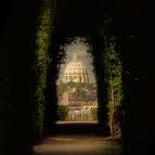 A photo of a capitol like building taken from hedge tunnel.