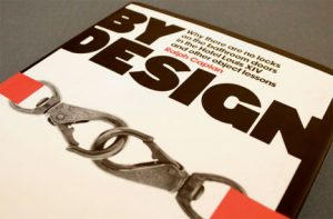 A photo of a book cover with two connected orange straps on it and the title: By Design.