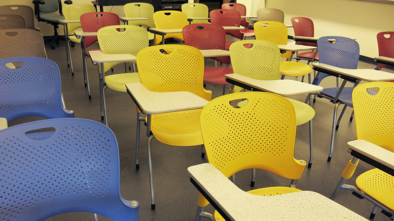 A photo of some empty and colorful classroom desks.