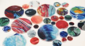 Colorful white, green, red, blue and yellow resin art put in different petri dishes.
