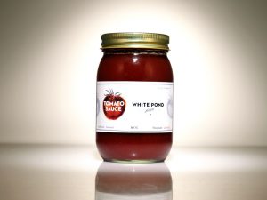 A glass jar filled with tomato sauce and a label with a tomato on it and the text White Pond.