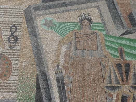 A mosaic picture of a person wearing, roman clothes, with a sword and a libra in each hand and a red star shining green rays behind.