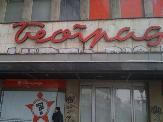A photo of an old store front with some red writing on top.