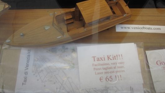 A photo of miniature wood boat alongside plans on how to ensemble it.