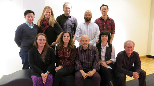 A photo of a group of people some sitting and some standing in an art gallery.