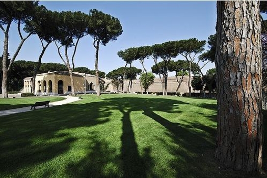 A photo of a green park with trees near some ancient stone buildings in Rome.