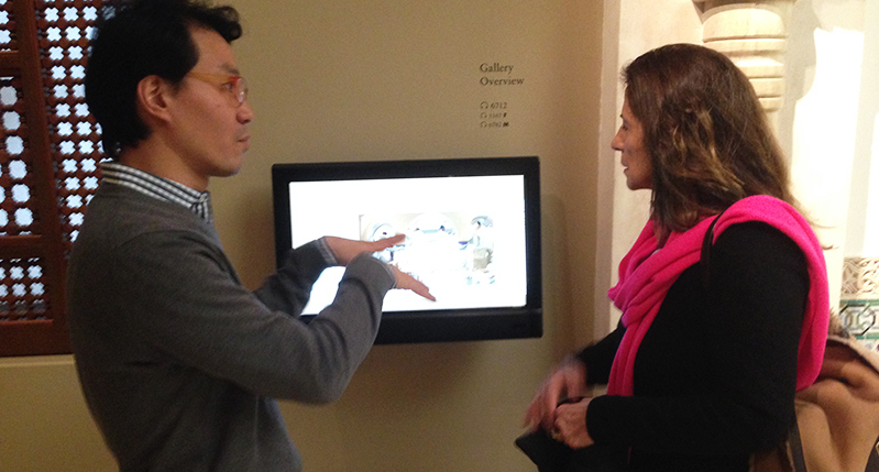 A photo of a man showing something on a tablet display while talking to a woman.