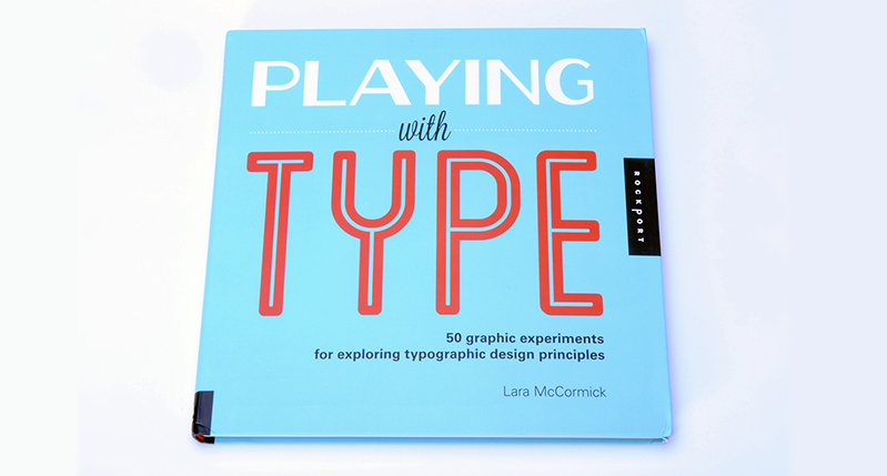 A photo of a cyan notebook with some white and red text that says: Playing with Type.