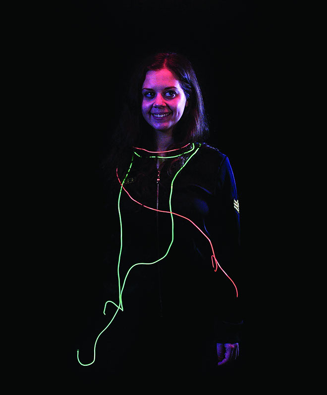 A smiling girl with red and green glowing wires around her.