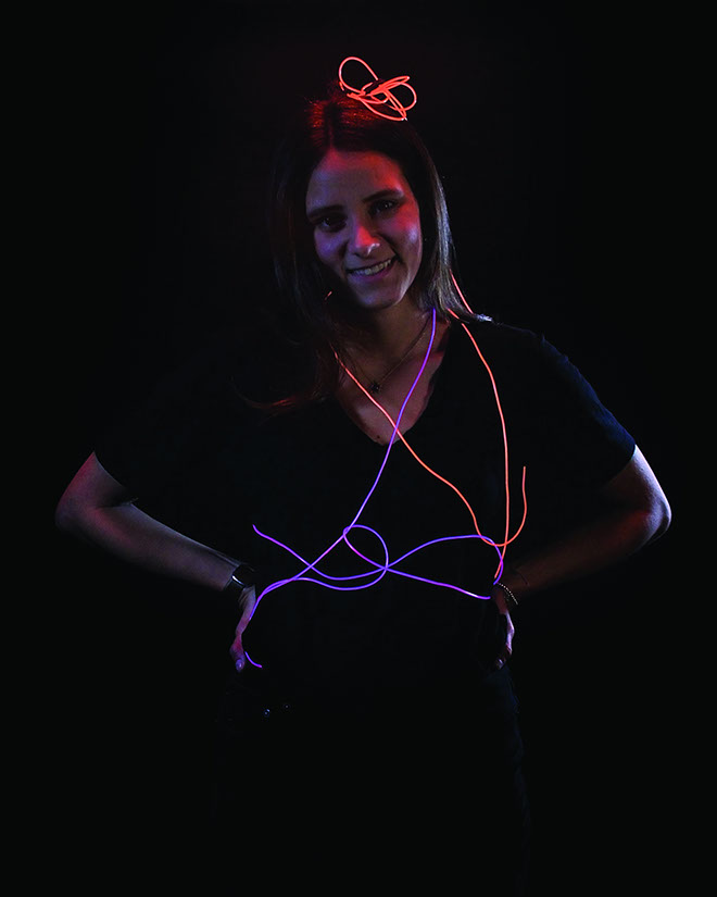 A smiling girl with red and blue glowing wires around and on top of her head.