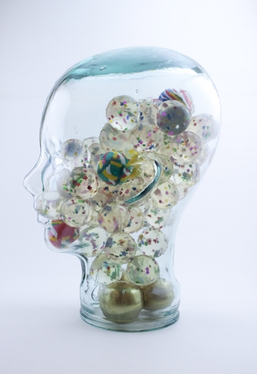 A human head made from glass filled with transparent and colored rubber balls.