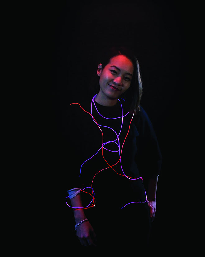 A smiling girl with red and blue glowing wires around her.