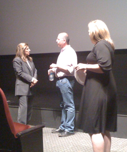 A photo of three persons talking on the stage.