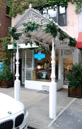 A photo showing a white stylized entrance with green leaves to a store.