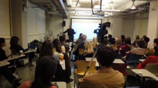 A photo of a classroom where a lecture is taking place and is being filmed.